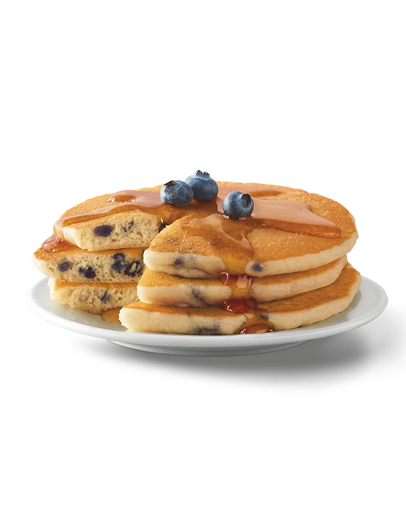 Eggo Pancakes package on a table with a plate of pancakes and waffles.